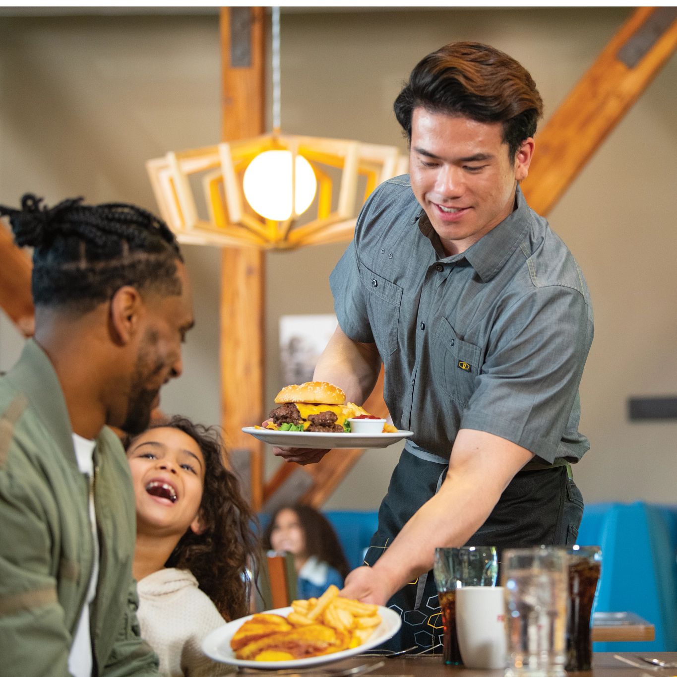 Male server placing food on a table for a family